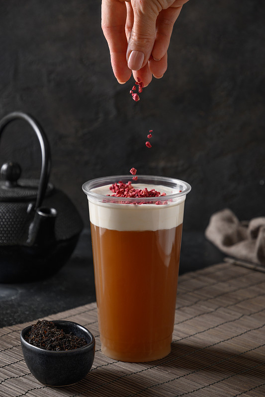 女人在芝士茶上撒上鲜奶油，淋上浆果。