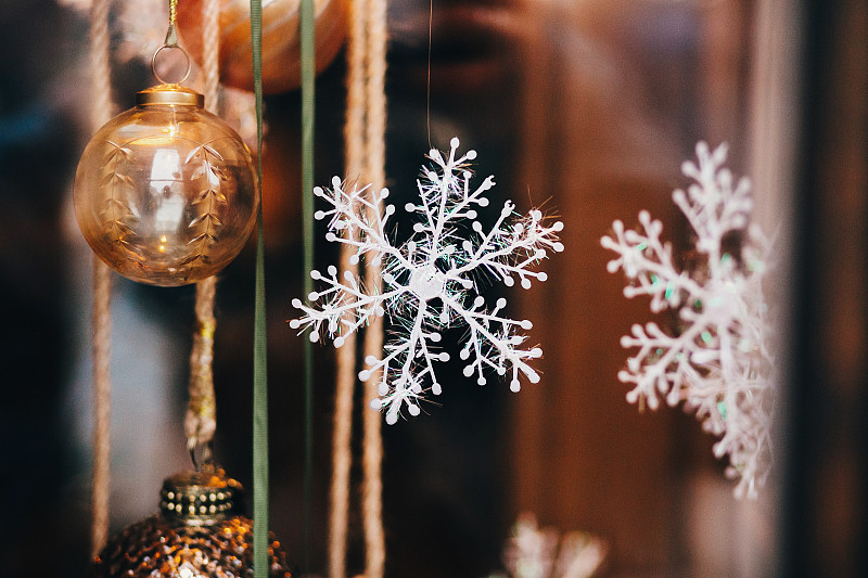 时尚的圣诞装饰品，雪花，橡子装饰，玩具在欧洲城市街道的窗口。城市中心的节日装饰，寒假