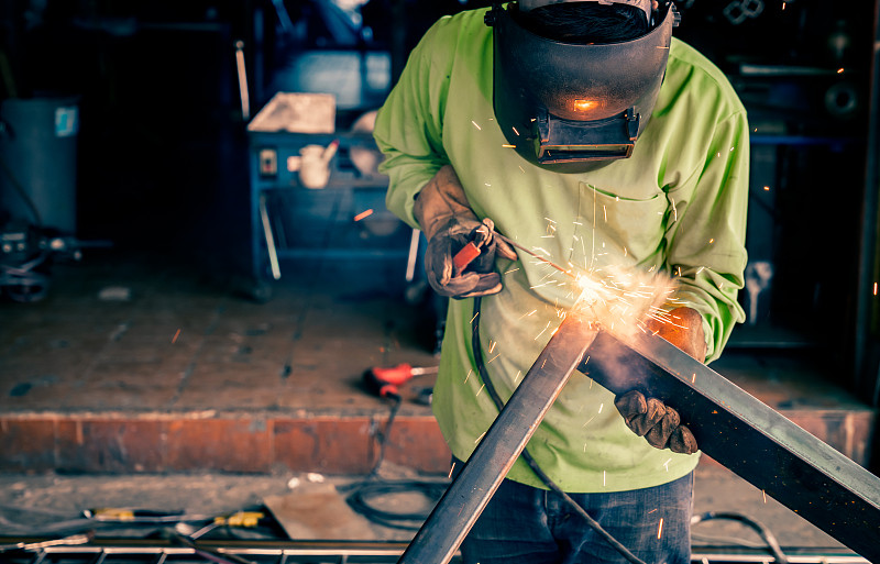 男工人正在使用电焊机。