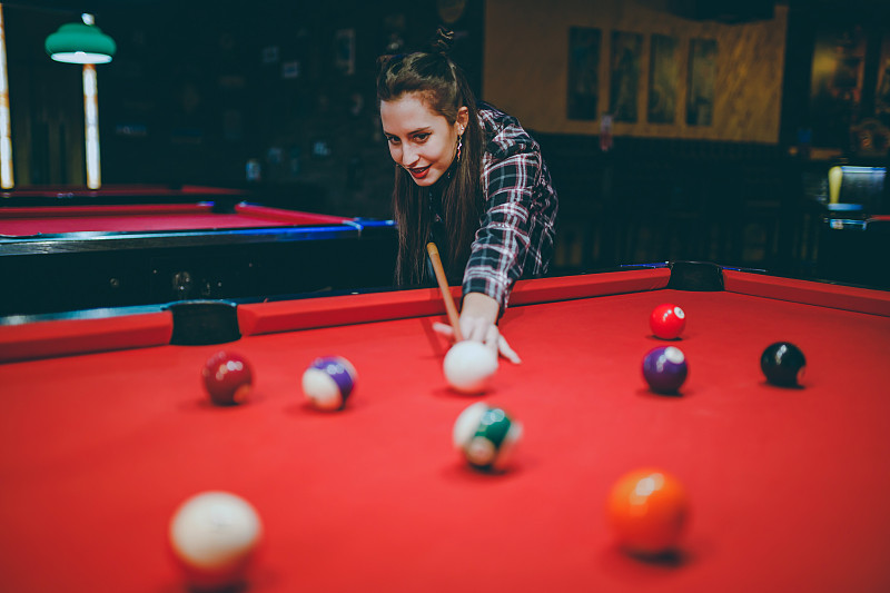 女人在酒吧里瞄准和打台球