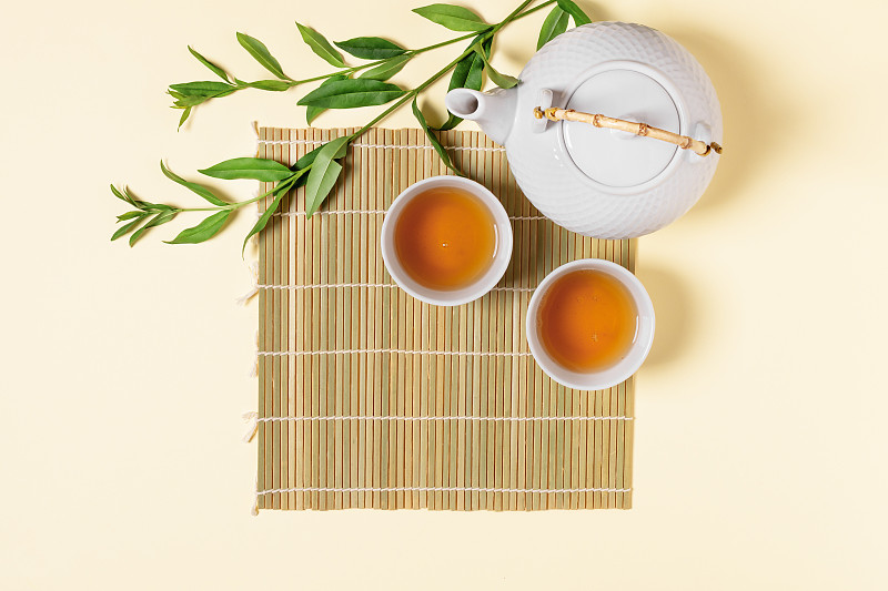 白色茶壶和茶杯与茶饮俯视图。