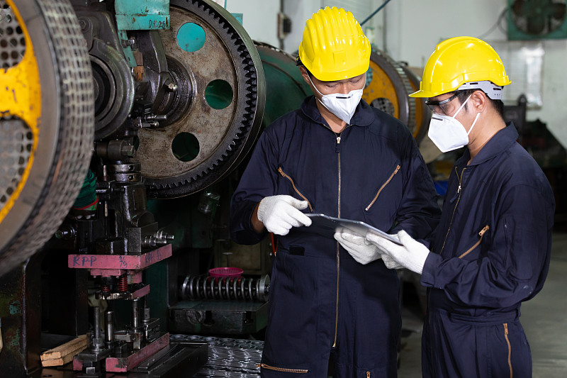 男工程师或工厂工人戴着防毒面具，谈论和使用平板电脑谈论项目