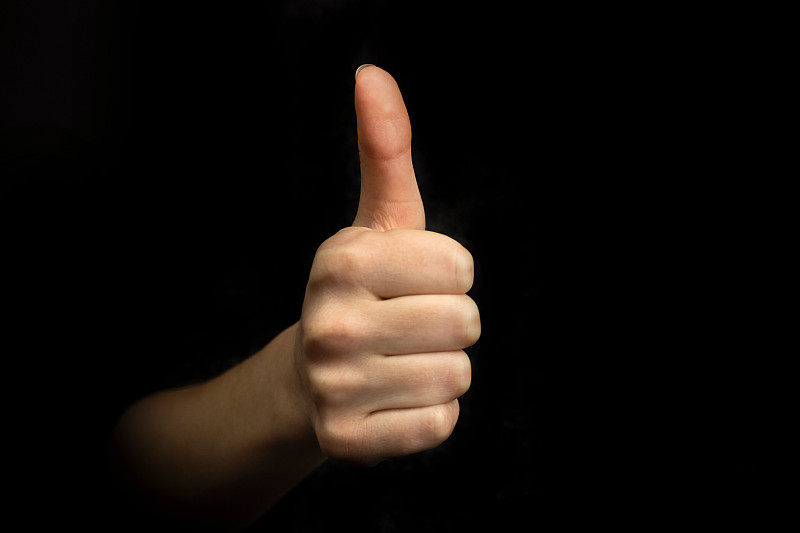 成功手势，在黑色背景上竖起大拇指的手势，商业概念照片