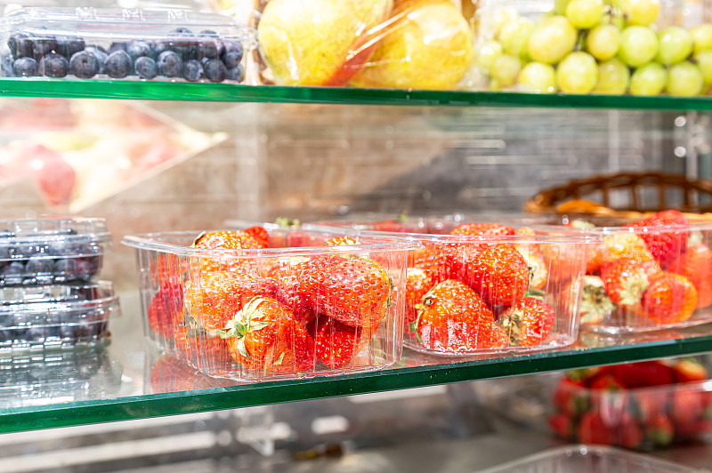 新鲜成熟的草莓和其他水果放在玻璃架子上