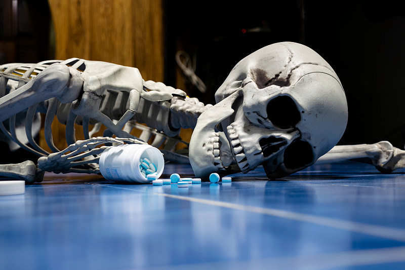 假湖南骷髅脸朝下躺在地板上，手里拿着药瓶。