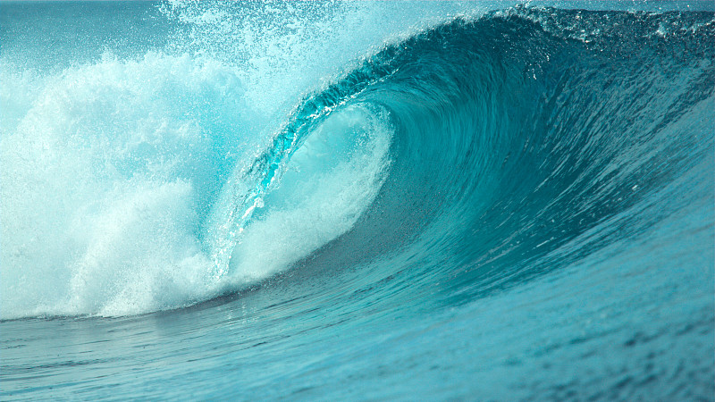 近距离观察:巨大的管状波浪汹涌地涌向太平洋上一个阳光明媚的热带岛屿。