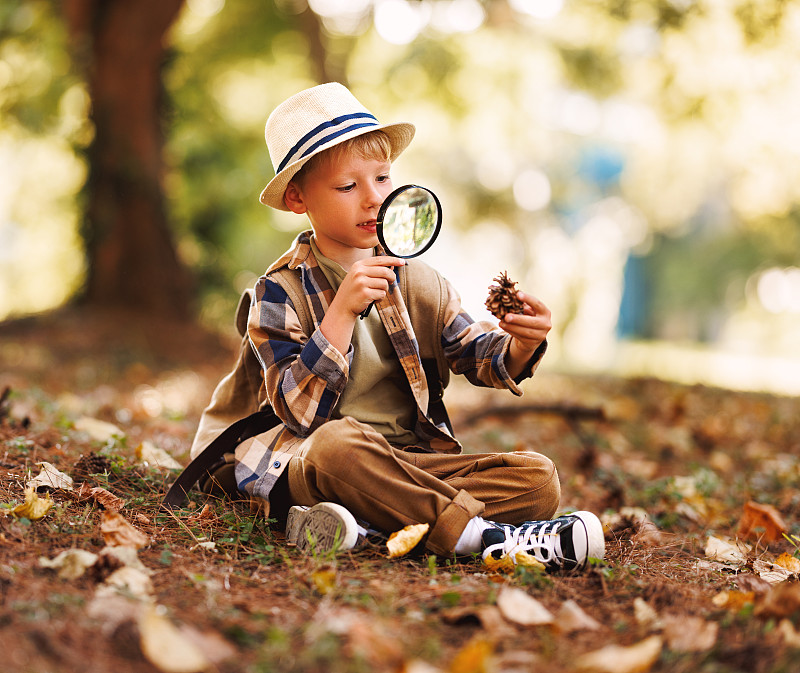 快乐快乐的男孩拿着放大镜在大自然中研究夏天的环境