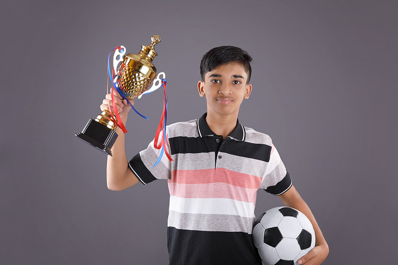一个印度学生拿着一个足球金杯