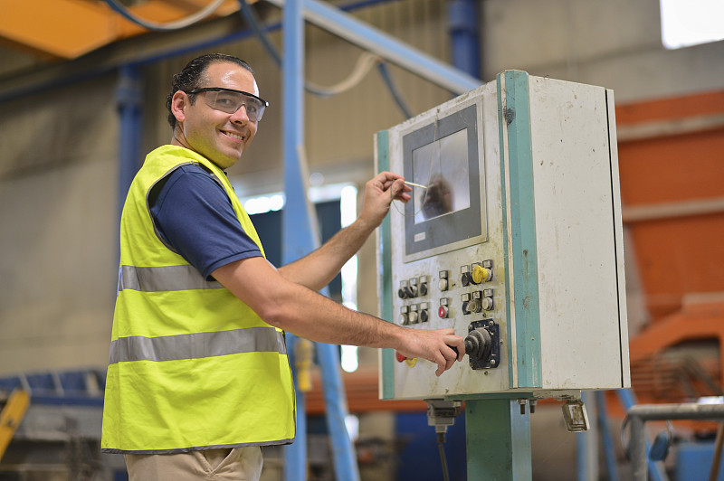 工人在工厂工作与控制面板和看的观点。西班牙科尔多瓦