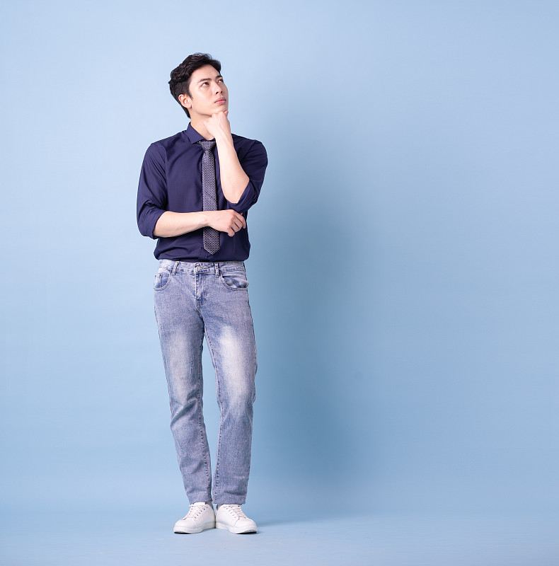 蓝色背景的年轻亚洲商人的全长形象