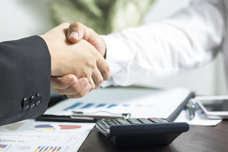 成功的商务谈判理念，商务人士完成会议后握手或设定目标和计划
