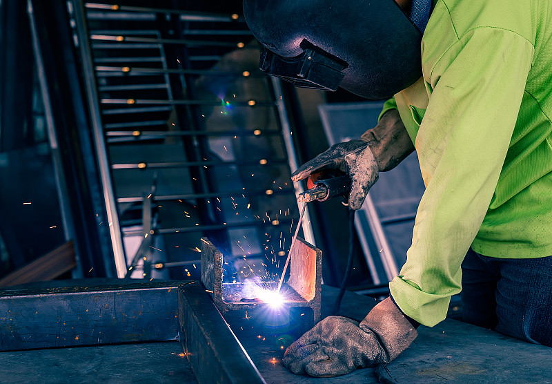 男工人正在使用电焊机。