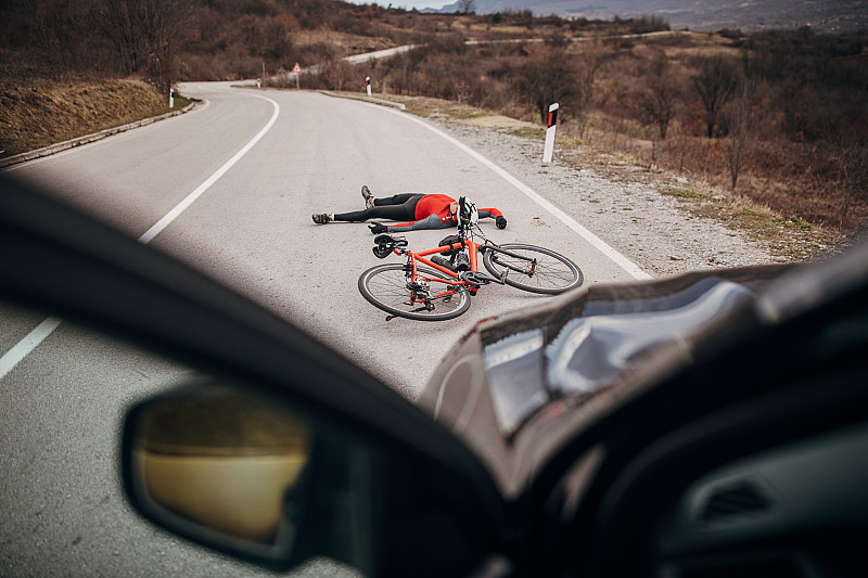 一个骑自行车的人被汽车撞了，躺在马路上