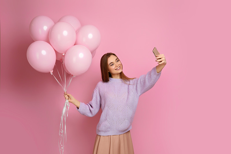 拿着粉色气球拿着智能手机的女孩