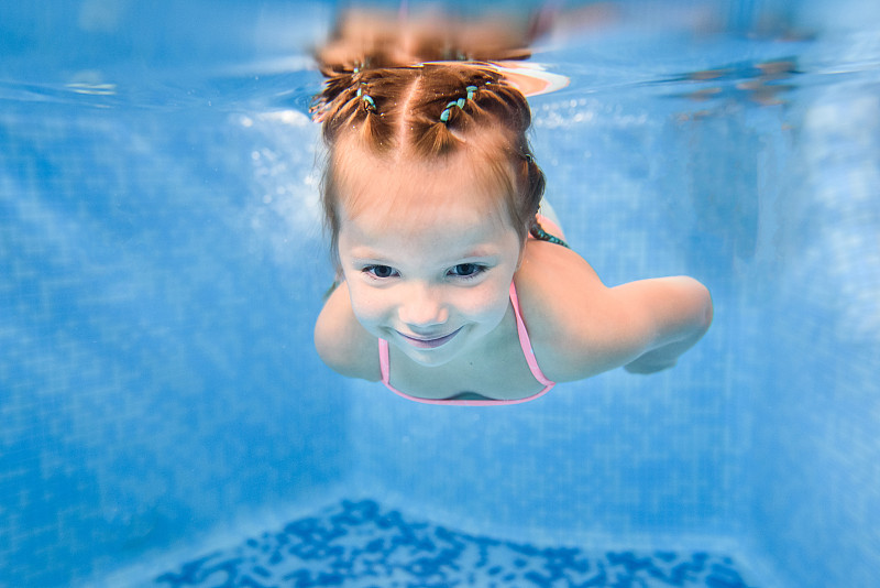 一个女孩在水里游泳。潜水。学孩子游泳。享受游泳和泡泡。