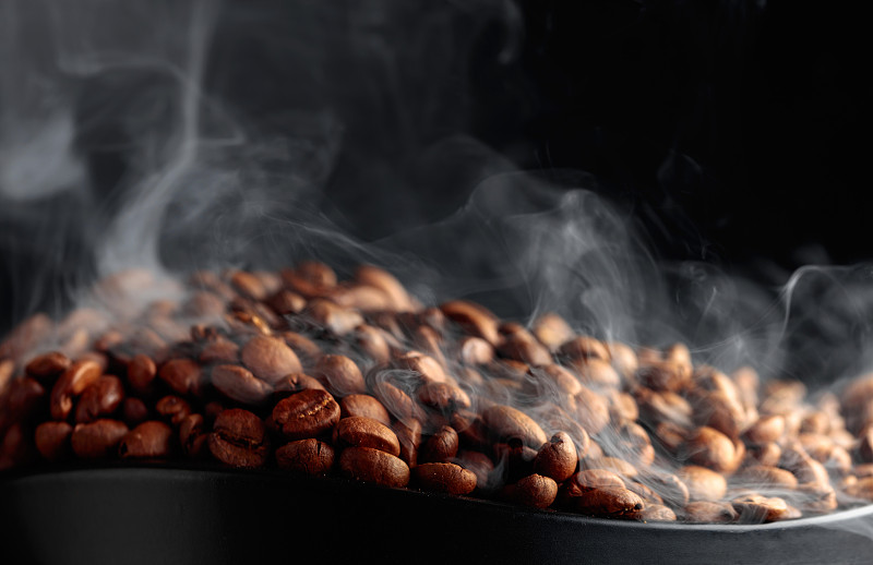 黑色背景上热气腾腾的咖啡豆。