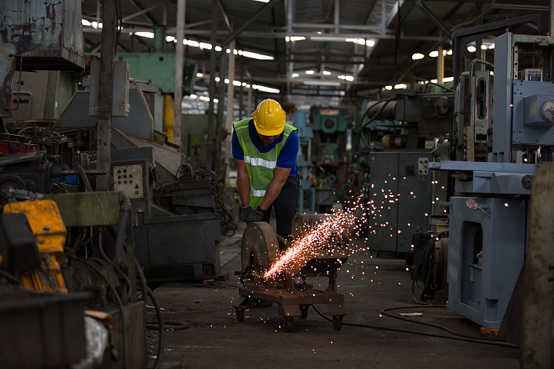 用金属锯工作的男性工人。亚洲男工程师，在工业工厂用复合斜切锯和圆刀片切割金属和钢铁