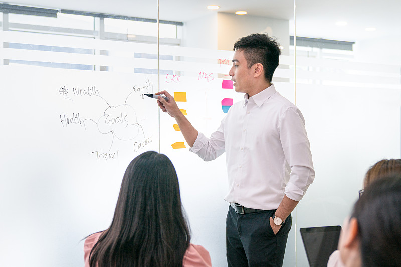 教练在白色的玻璃板上给观众做演示。