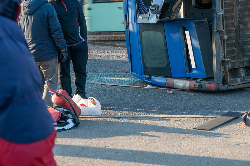 一辆倒车的蓝色小货车在路上，人们的双腿离得很近
