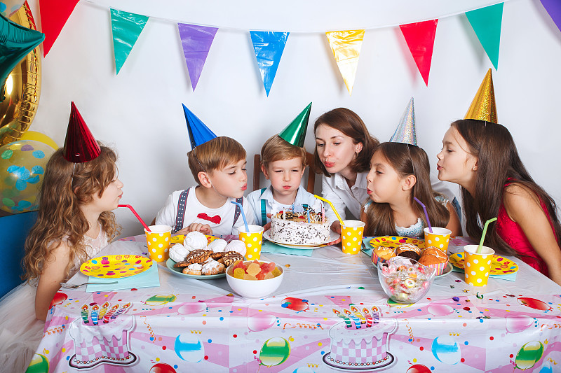 家庭生日聚会。女孩和她的兄弟姐妹吹蜡烛
