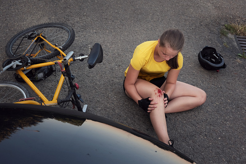 一名年轻女孩在车祸后骑自行车坐在路上