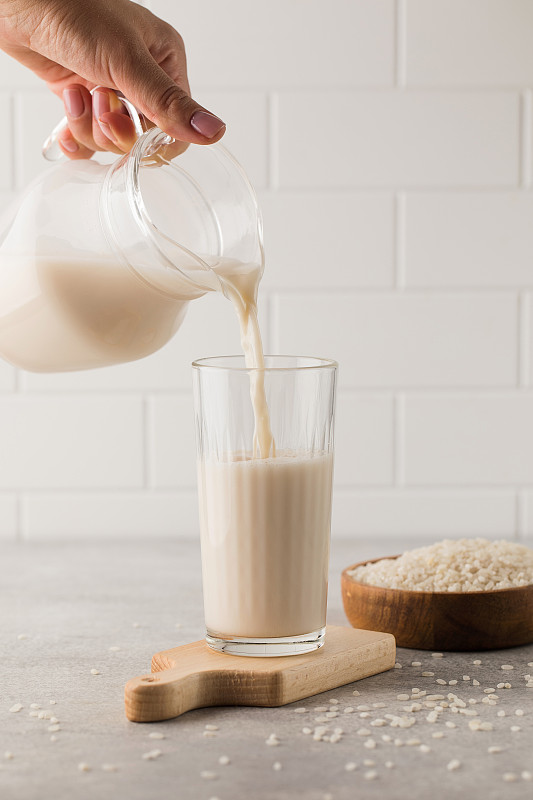 蔬菜米奶从罐子里倒进玻璃杯里。替代牛奶。