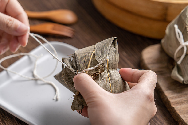 吃粽子-端午节粽子年轻的亚洲妇女吃中国传统食物在家里的木桌庆祝。