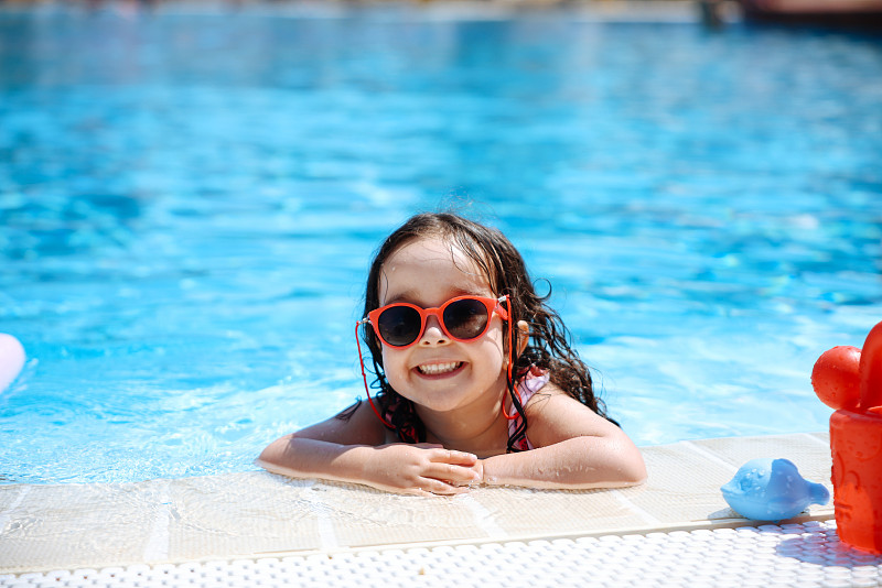 快乐的笑着蹒跚学步的女孩在游泳池里玩耍