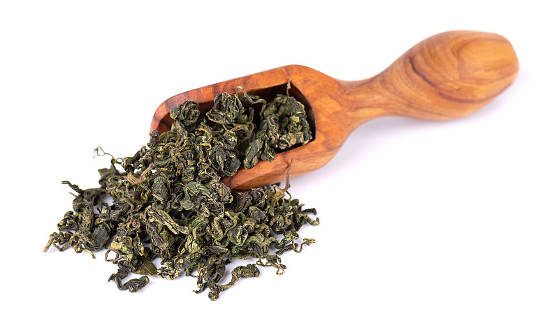 干燥绞股蓝叶在橄榄勺里，离生在白色黑土上。焦谷兰或奇迹草。中国花草茶。