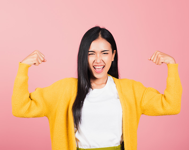 女人举起手臂，肱二头肌，自信地展示力量