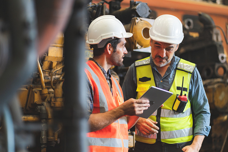 在工业制造工厂工作的带安全帽、安全帽、安全帽的专业技术人员，负责检查机械设备、生产技术或施工操作