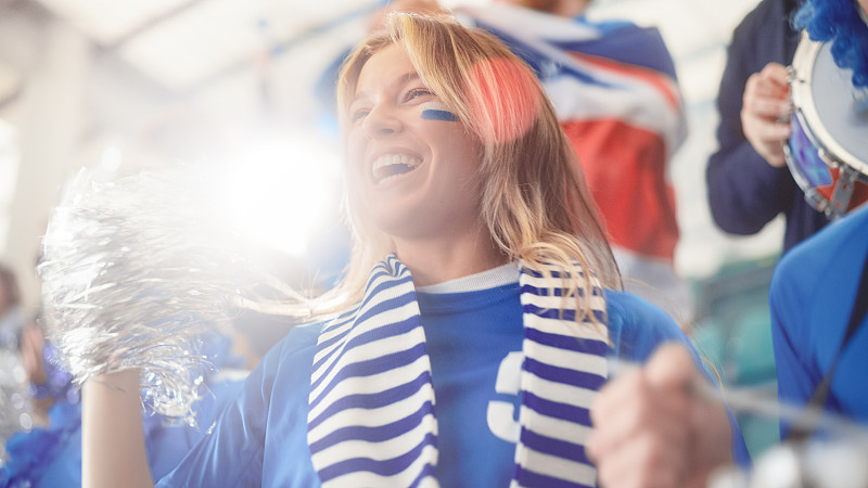 体育场馆大事件:美丽的助威女孩。一群脸上涂满彩绘的球迷为他们的蓝色足球队欢呼、呐喊。人们庆祝进球，冠军