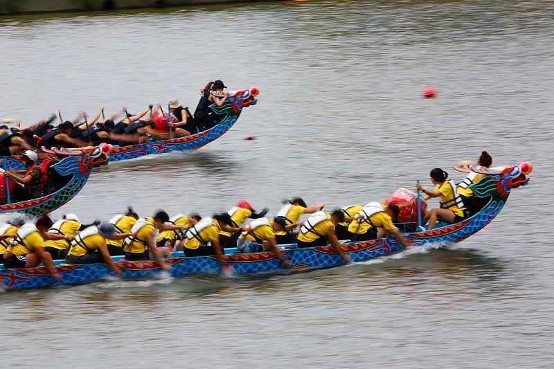 图为台湾台北端午赛艇比赛现场，运动员们奋力划桨，在五颜六色的传统龙舟上奋力比赛