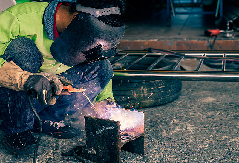 男工人正在使用电焊机。
