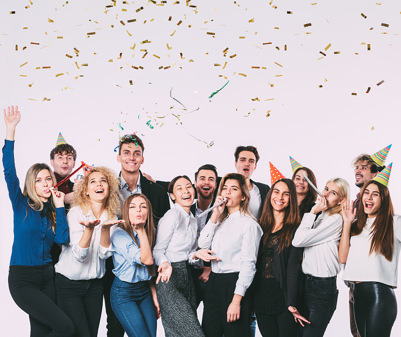 快乐微笑的年轻人拿着礼盒，吹着派对哨子。