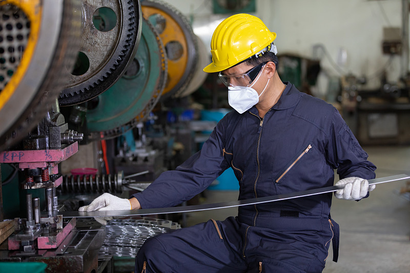 在工厂工作的男性技术员或工厂工人戴口罩以保护病毒