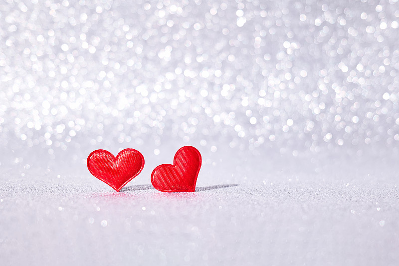 红色的心在银色模糊抽象背景与散景。情人节的概念。贺卡。