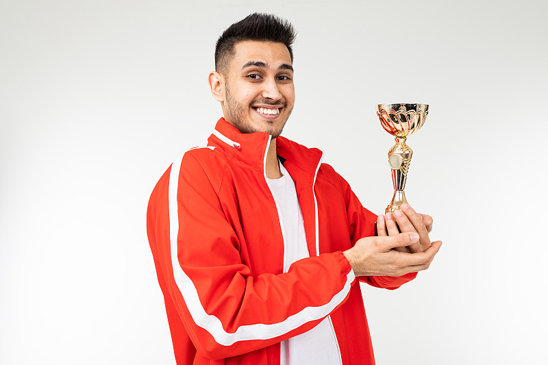 快乐的运动员在一个白色的演播室背景上的金杯运动套装