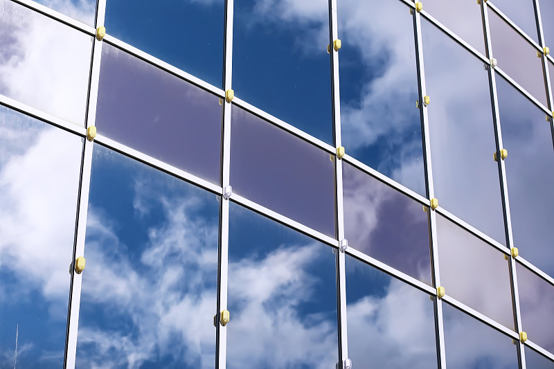 立面的建筑细节与其他建筑和太阳的多重反射。现代建筑。架构的背景