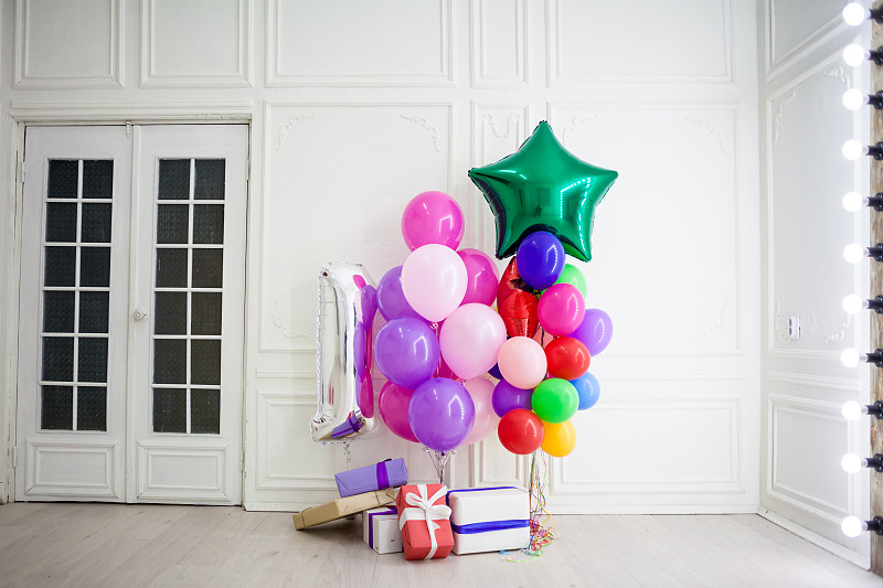 房间里放着不同颜色的气球，上面放着节日的礼物
