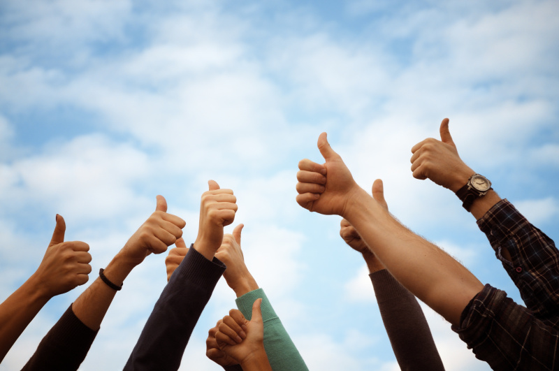 一群人向蓝天竖起大拇指。本空间