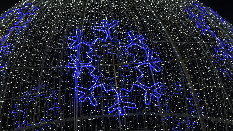 蓝色发光球，花环和雪花。圣诞花环盘绕在一个大的球形钢框架上。