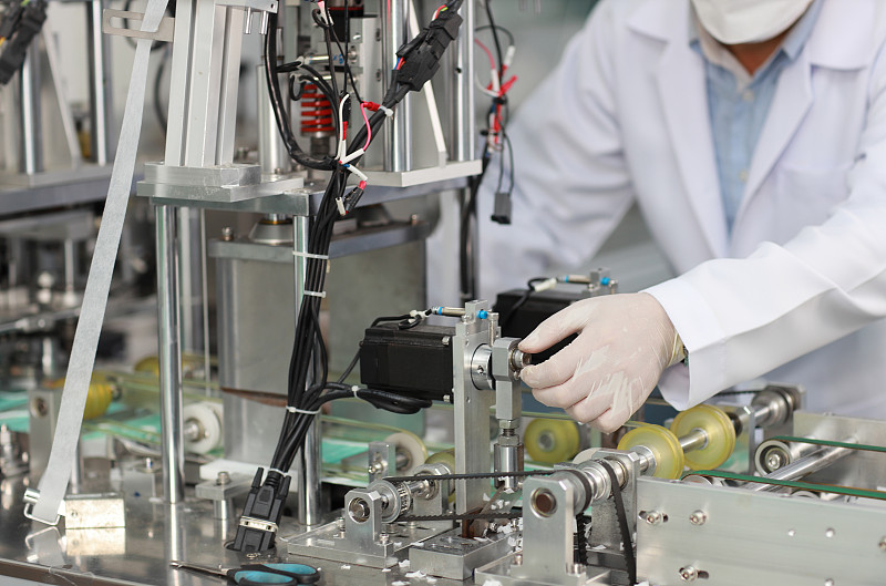 检验员或工人手拿丁腈手套做口罩质量和医用口罩生产线，工业和工厂概念。