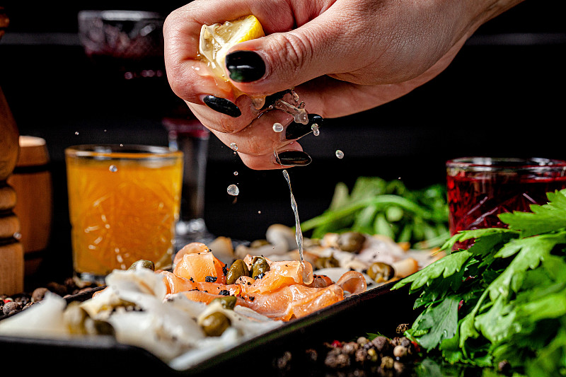 欧洲人,葡萄牙菜。三文鱼片、油鱼、大比目鱼及柠檬的开胃菜。背景图像，复制空间文本