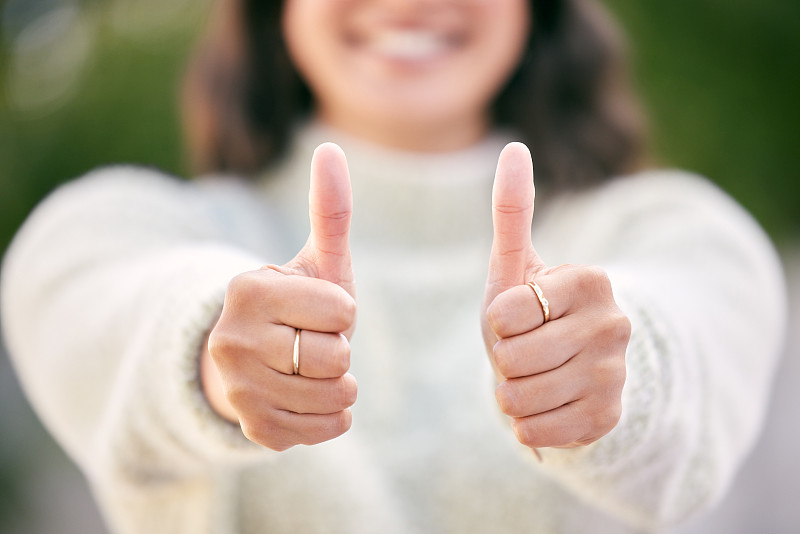 一名女子站在外面竖起大拇指