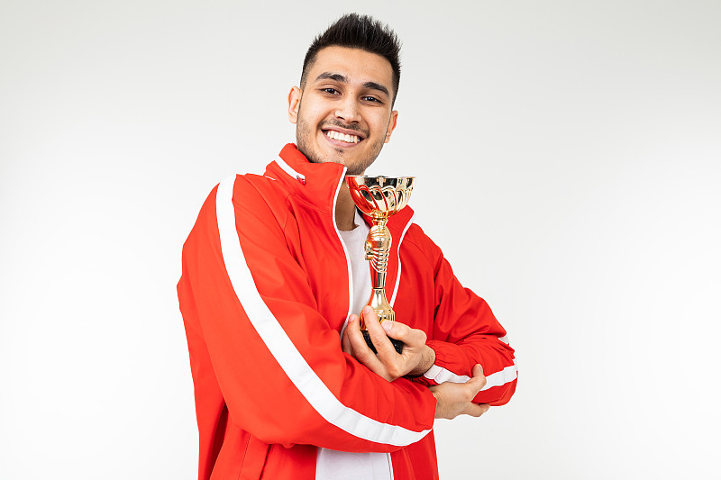 快乐的运动员在一个白色的演播室背景上的金杯运动套装