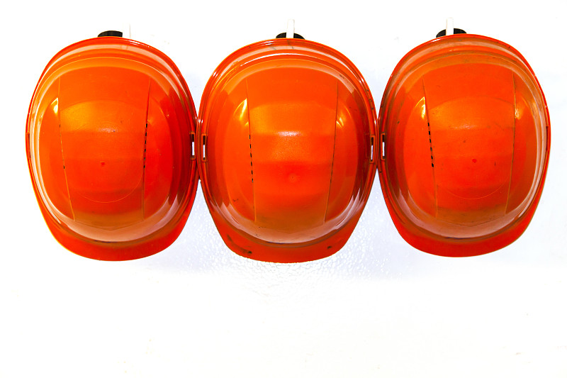 白色墙上的挂钩上挂着橙色的安全帽。