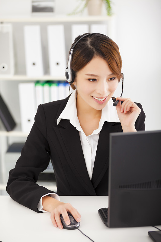 年轻的女商人戴着耳机在办公室工作