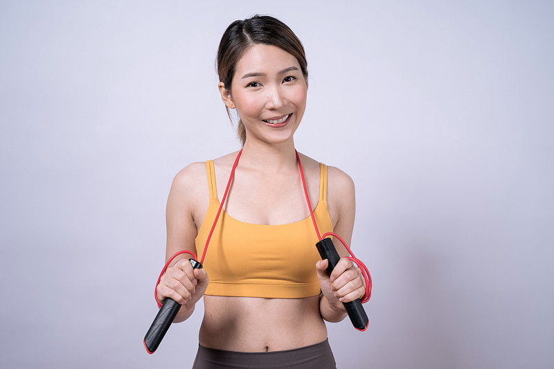 亚洲女子抱着跳绳设备孤立在白色的背景下，健康的运动理念。