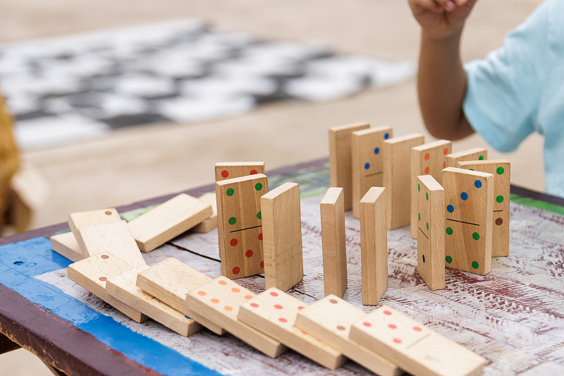 男孩在外面玩木头多米诺骨牌